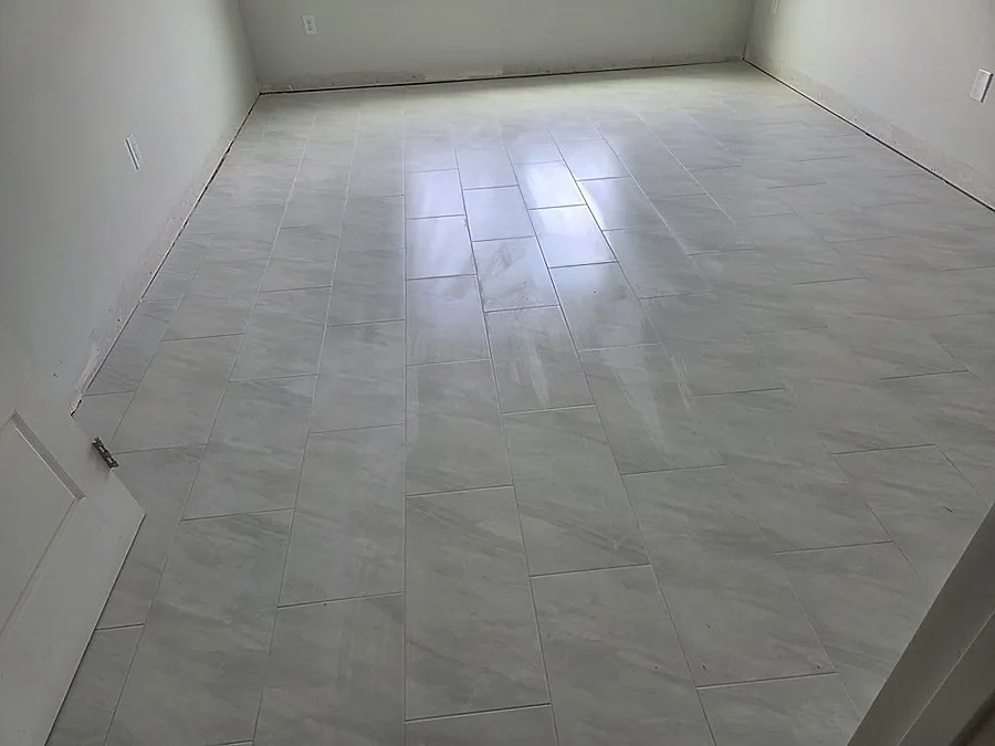 Large-format gray marble-look floor tile laid across an empty living room