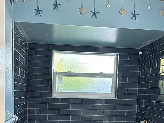 Shower lined in dark charcoal subway tile with a pebble floor