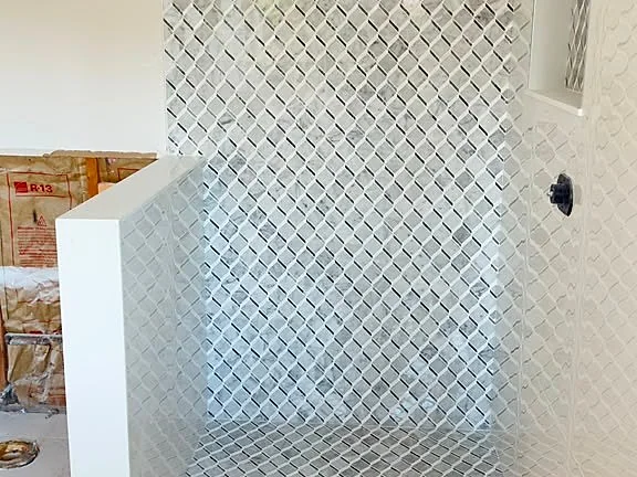 Shower wall in diamond-pattern mosaic tile with a matching mosaic floor