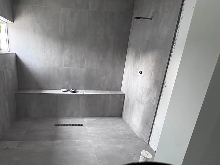 Shower in gray concrete-look large-format tile with a built-in bench