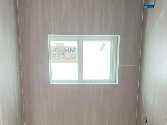 Bathtub with a vertical stone-look tile surround under a small window