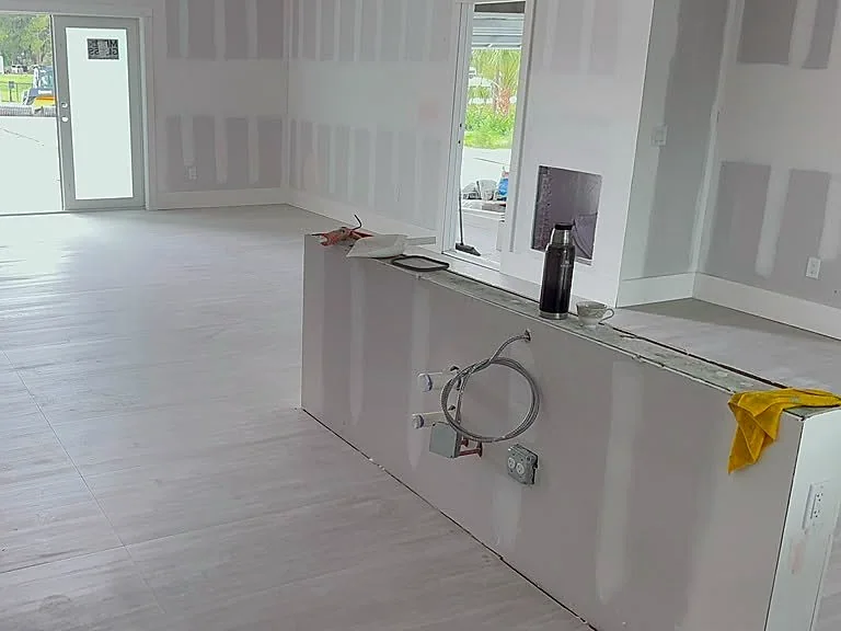 Open living and kitchen area with wood-look plank flooring at the drywall stage