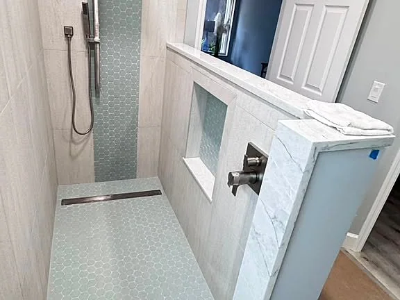 White panel door installed beside a finished tiled shower with a glass mosaic accent