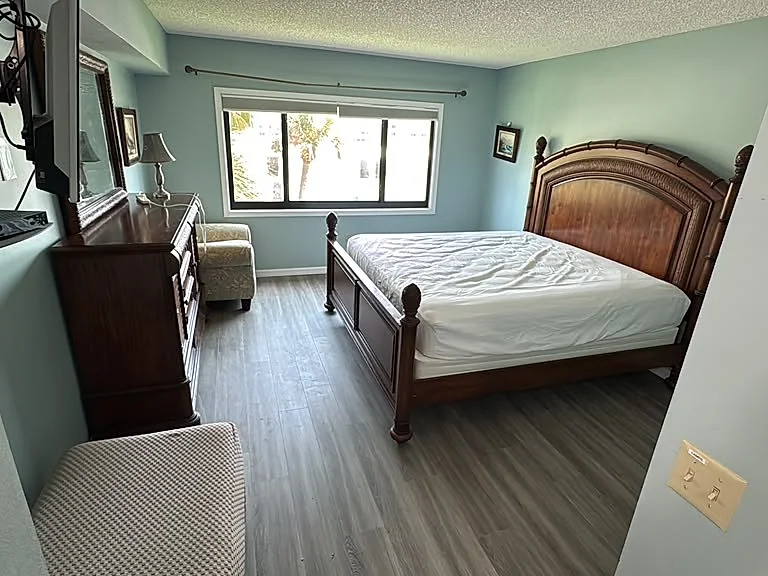 Bedroom with freshly painted sage green walls, wood-look plank flooring and white baseboard